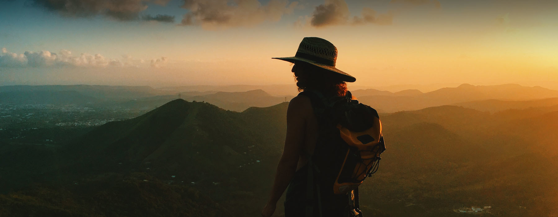 A traveler overlooking a mountain landscape at sunset, the original Local Guest banner photograph